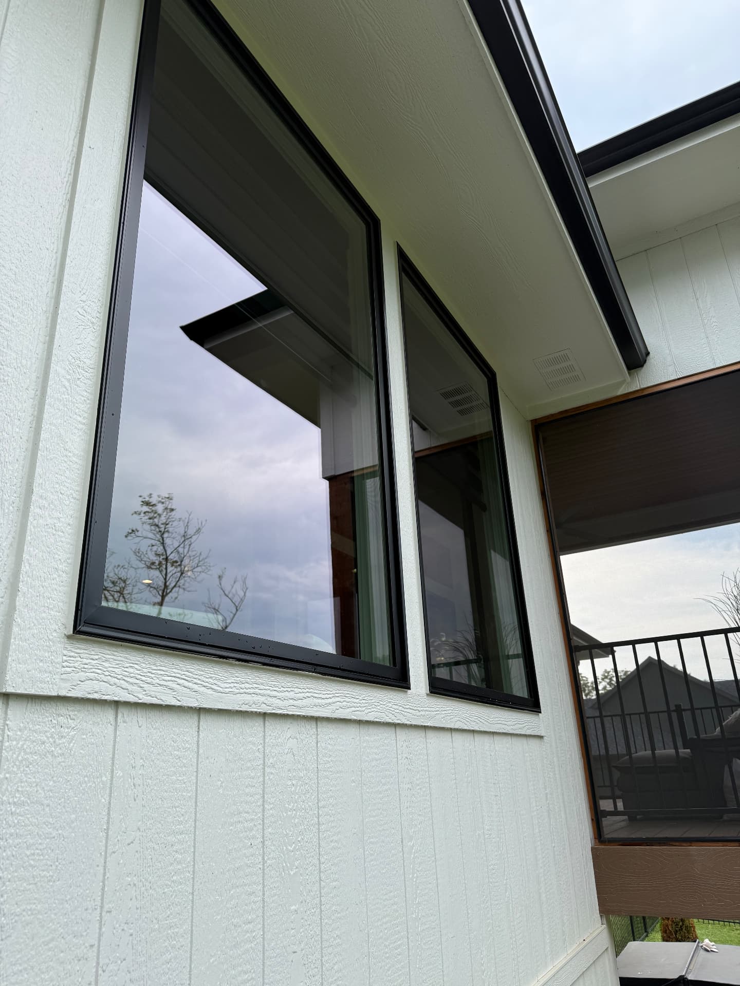 Black-framed picture windows cleaned on white board and batten siding