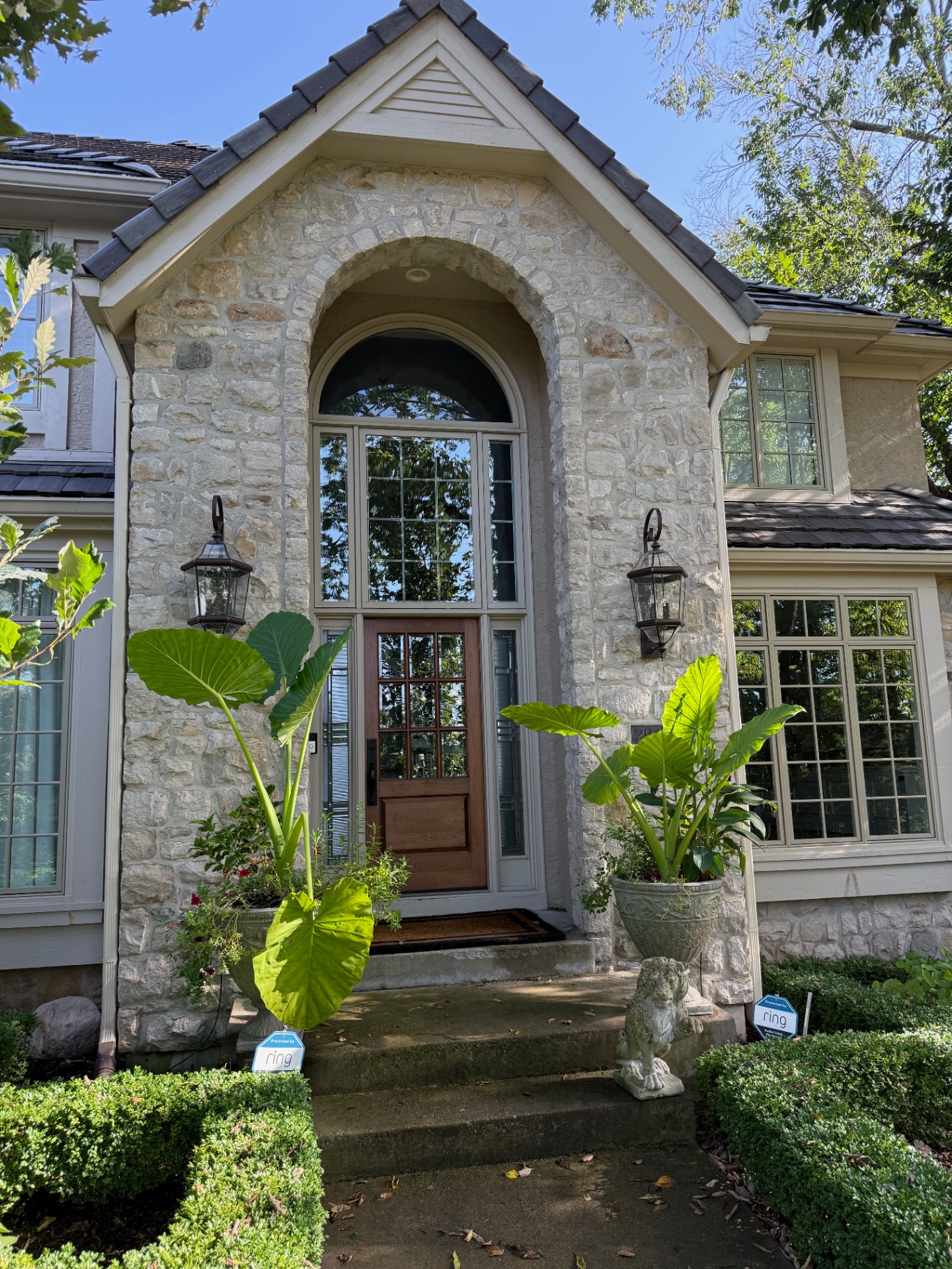 Stone-front entryway with arched wood door and spotless divided-light windows