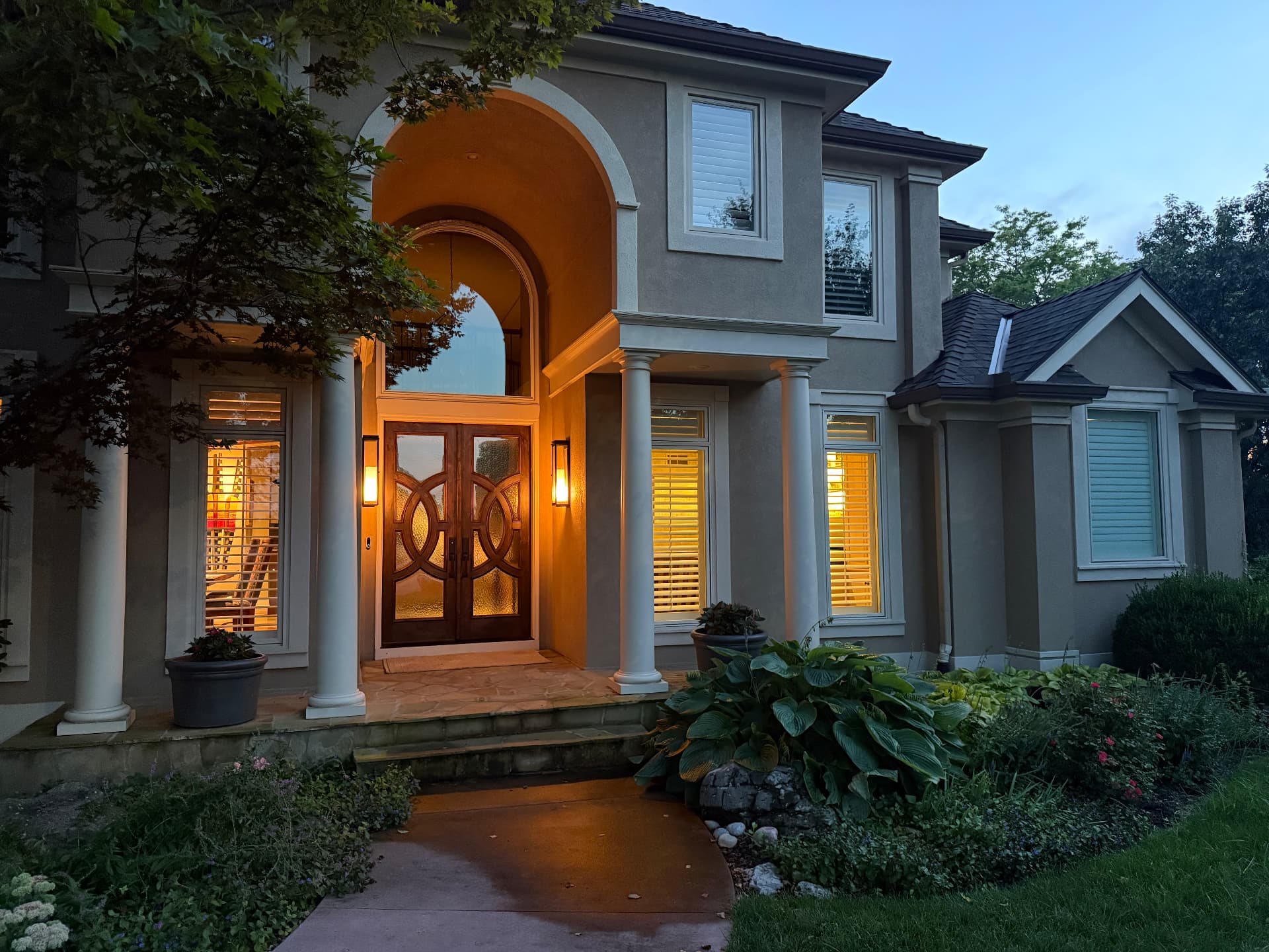 Arched stucco entryway with warm evening lighting and spotless glass front doors