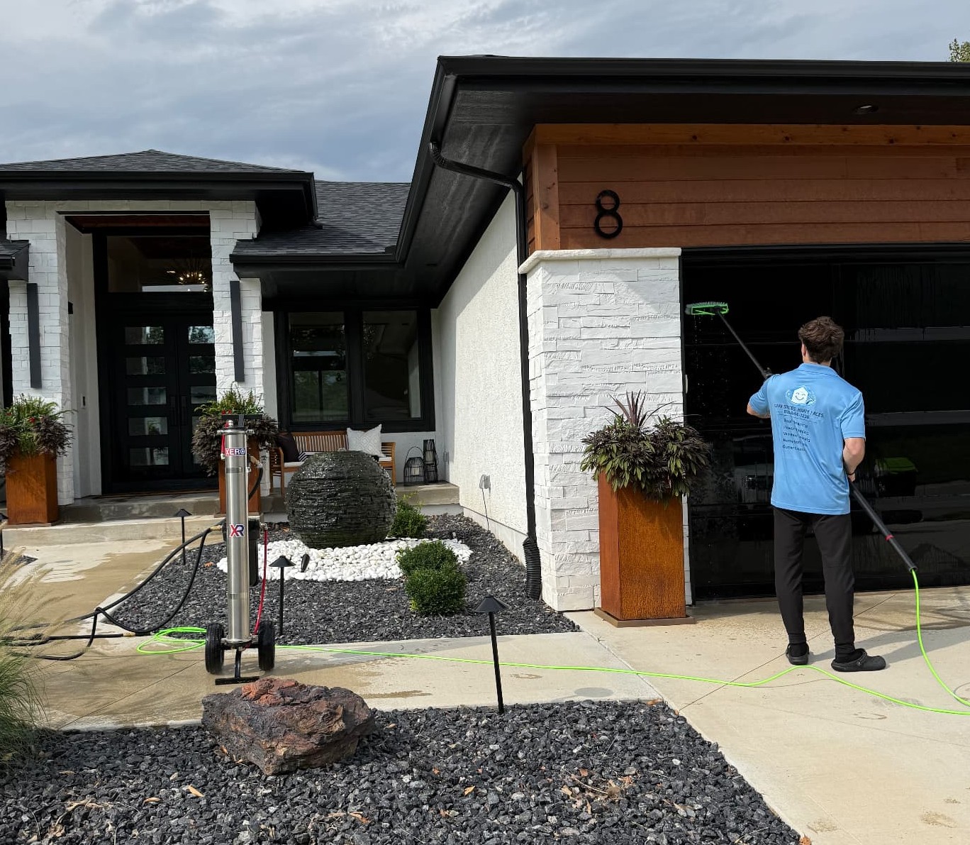 Happy Home Services technician using a XERO Pure Package water-fed pole system to clean windows on a Kansas City home